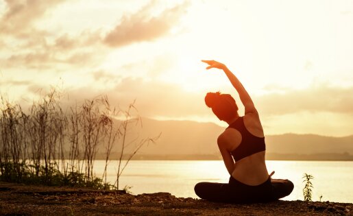 Frau sitzt am See Morgendämmerung in Yoga Pose